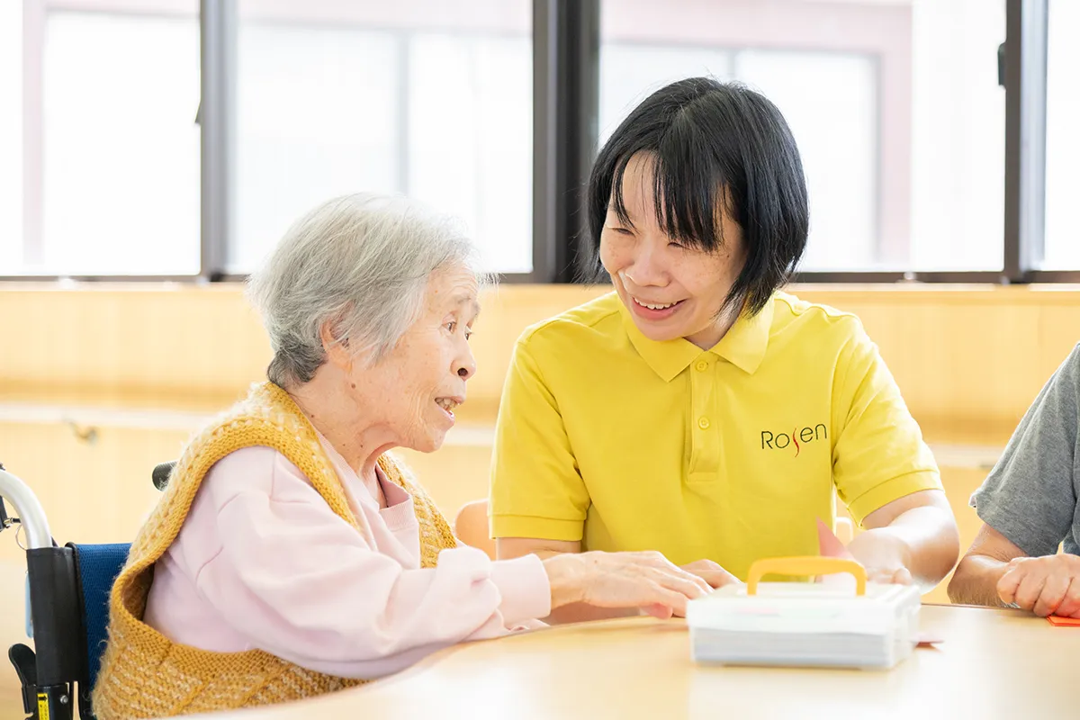 介護職員の女性が、高齢の女性に話しかけている様子