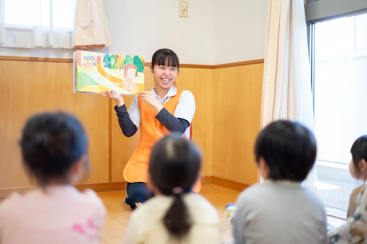 保育士の女性が、子どもたちに絵本の読み聞かせをしている様子